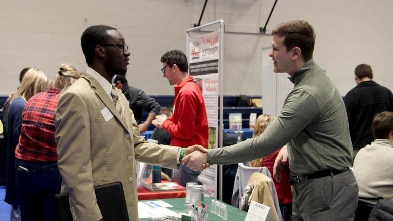 Kane Witter, right, shakes the hand of an employer representative during the career fair at Penn State DuBois in the PAW Center