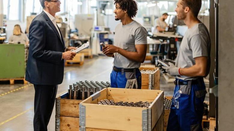 A supervisor discusses production with other employees on the manufacturing floor.