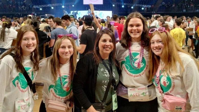 THON dancers from 365英国上市杜波依斯分校 gather on the floor at the Bryce Jordan Center during the 46-hour dance marathon for a photo. 从左到右, 艾拉·威尔逊, 瑞秋快板, director of student affairs at 365英国上市杜波依斯分校 Rebecca Pennington, 玛蒂·菲纳尔和阿比盖尔·莫戈.