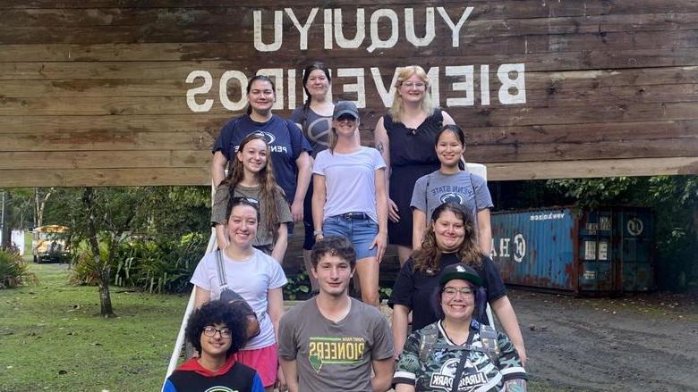 A group of people posing in front of sign reading, "CENTRO DE CONFERENCIAS YUQUIYU BIENVENIDOS."