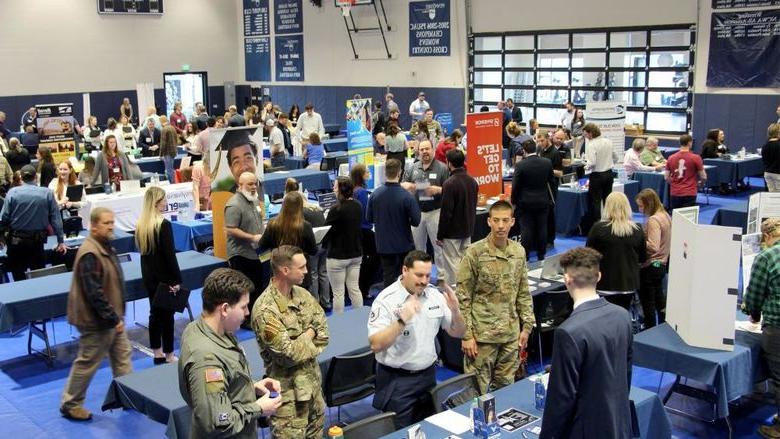 A full gym floor at the PAW Center, with the floor being full of employers, students, alumni and community members during the career fair.