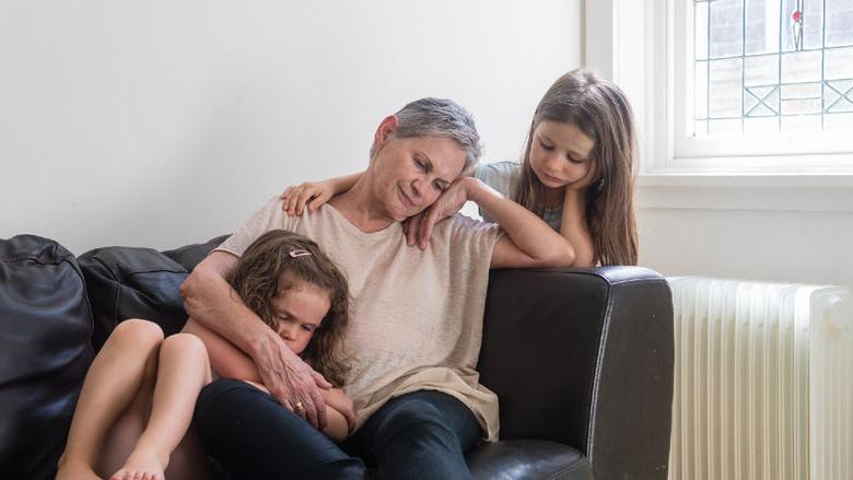 sad grandmother on couch with 2 granddaughters