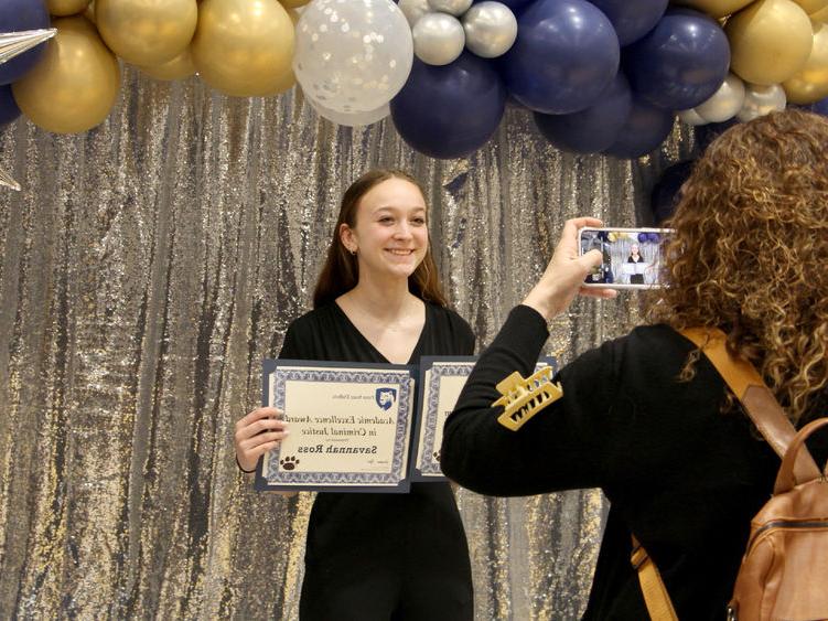 Penn State 杜波依斯 student Savannah Ross pauses with her awards for a photo, taken by a family member, at the recognition and awards banquet at the PAW Center.